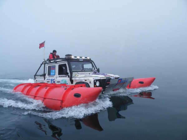 Cape-to-Cape远征的路虎Defender 110在白令海峡水面航行，红色浮筒展开