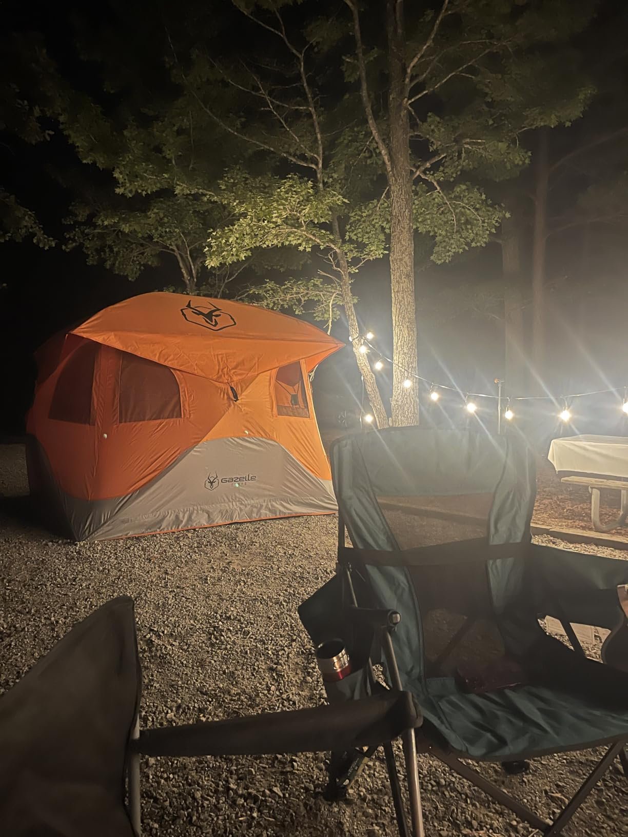 夜晚露营地里的橙色帐篷与绿色折叠椅