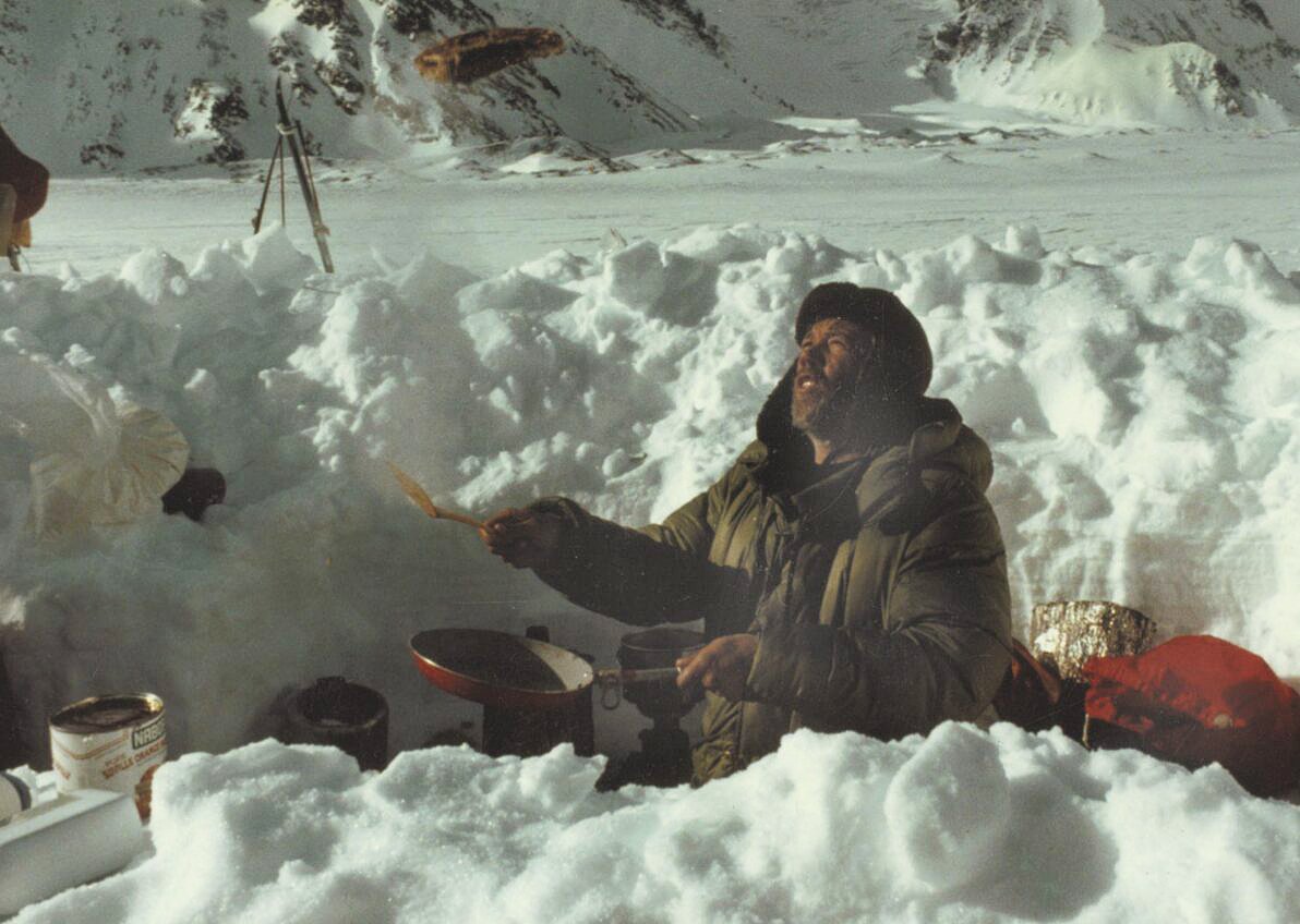 男子在雪山雪坑中穿着厚衣做饭