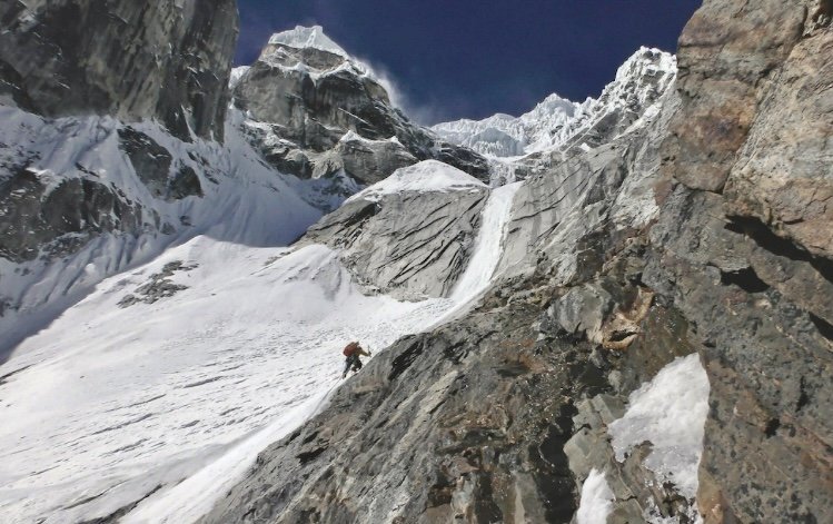 登山者攀爬雪山陡峭岩壁