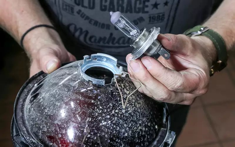 男子手持汽车大灯灯泡与透明灯罩