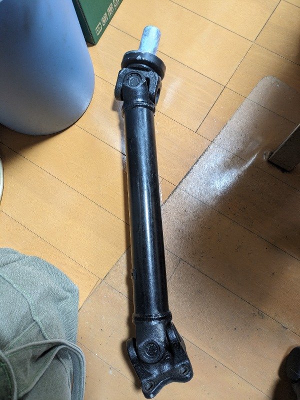 黑色汽车传动轴放置在木地板上的特写
