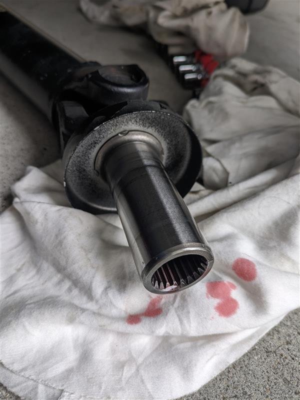 黑色汽车传动轴放在带红色污渍的白布上