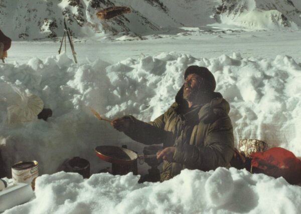 男子在雪山雪坑中穿绿衣做饭