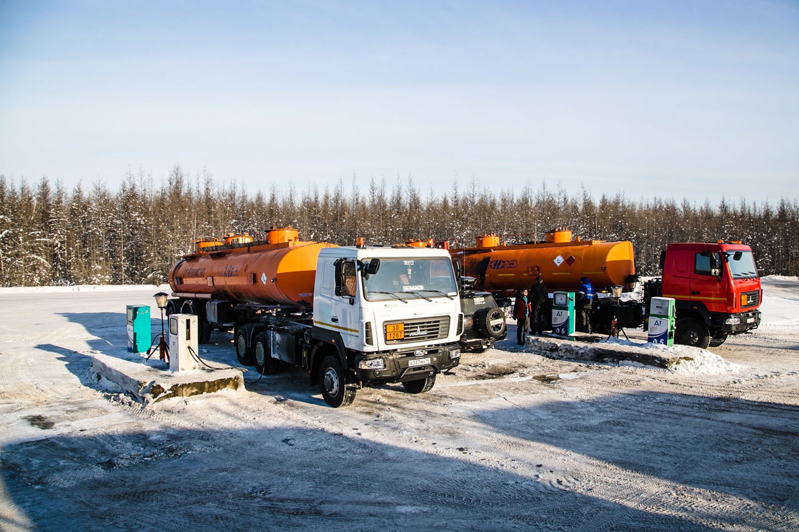 雪地中停放着橙罐白车头与红车头油罐车