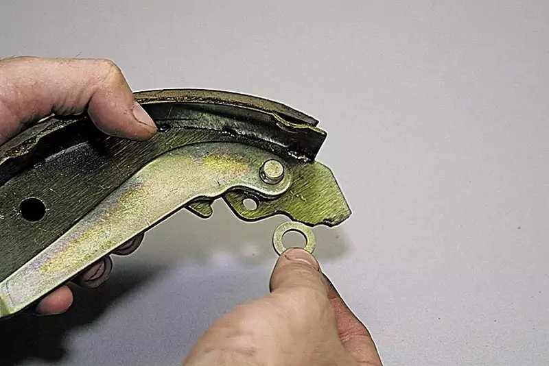 双手在白色背景下展示金色金属刹车片零件