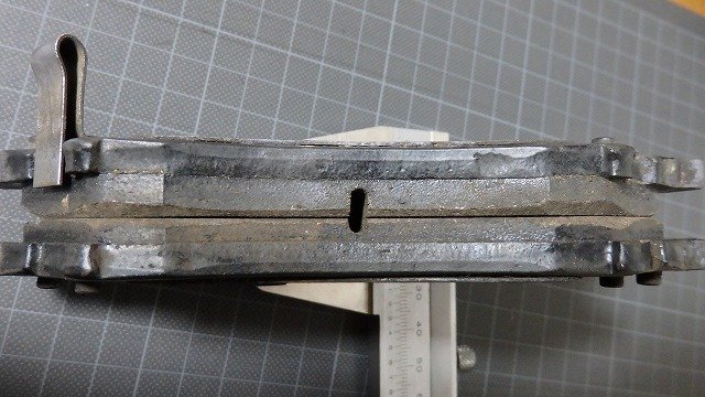 灰色金属零件置于网格垫上用游标卡尺测量