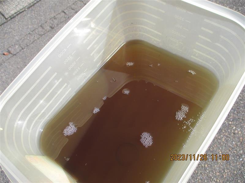 透明量桶装着褐色液体放在户外地面