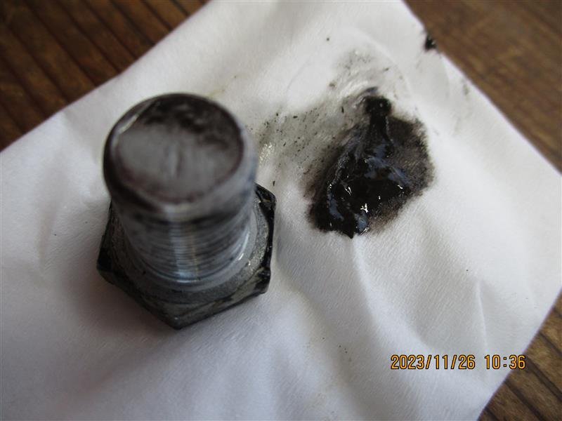 沾满黑色油污的金属螺丝放在白纸巾上