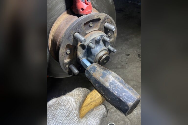 戴手套者用锤子敲击汽车轮毂上的金属工具