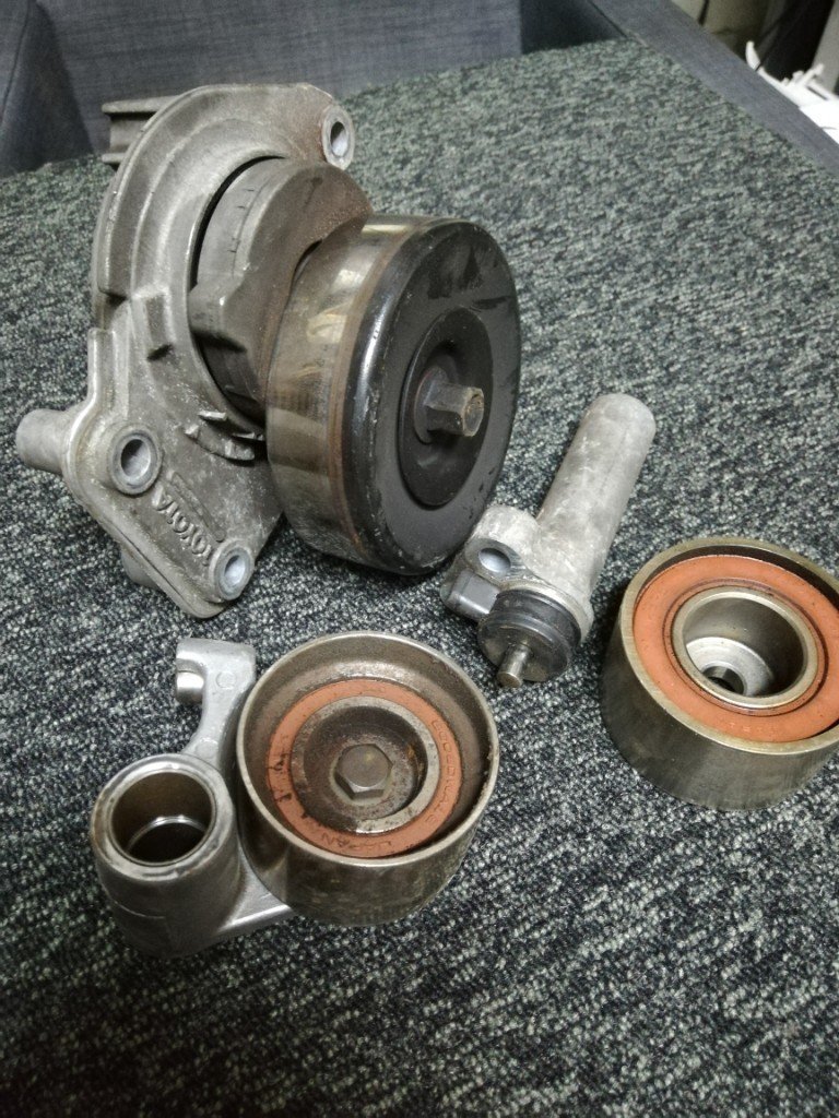 灰色汽车皮带轮及张紧器零件置于地毯上