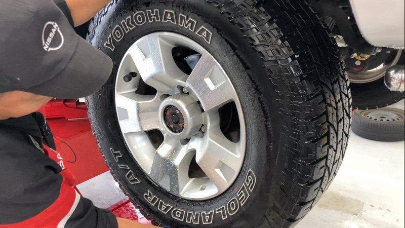 技师在车间为黑色越野车安装银色轮毂轮胎