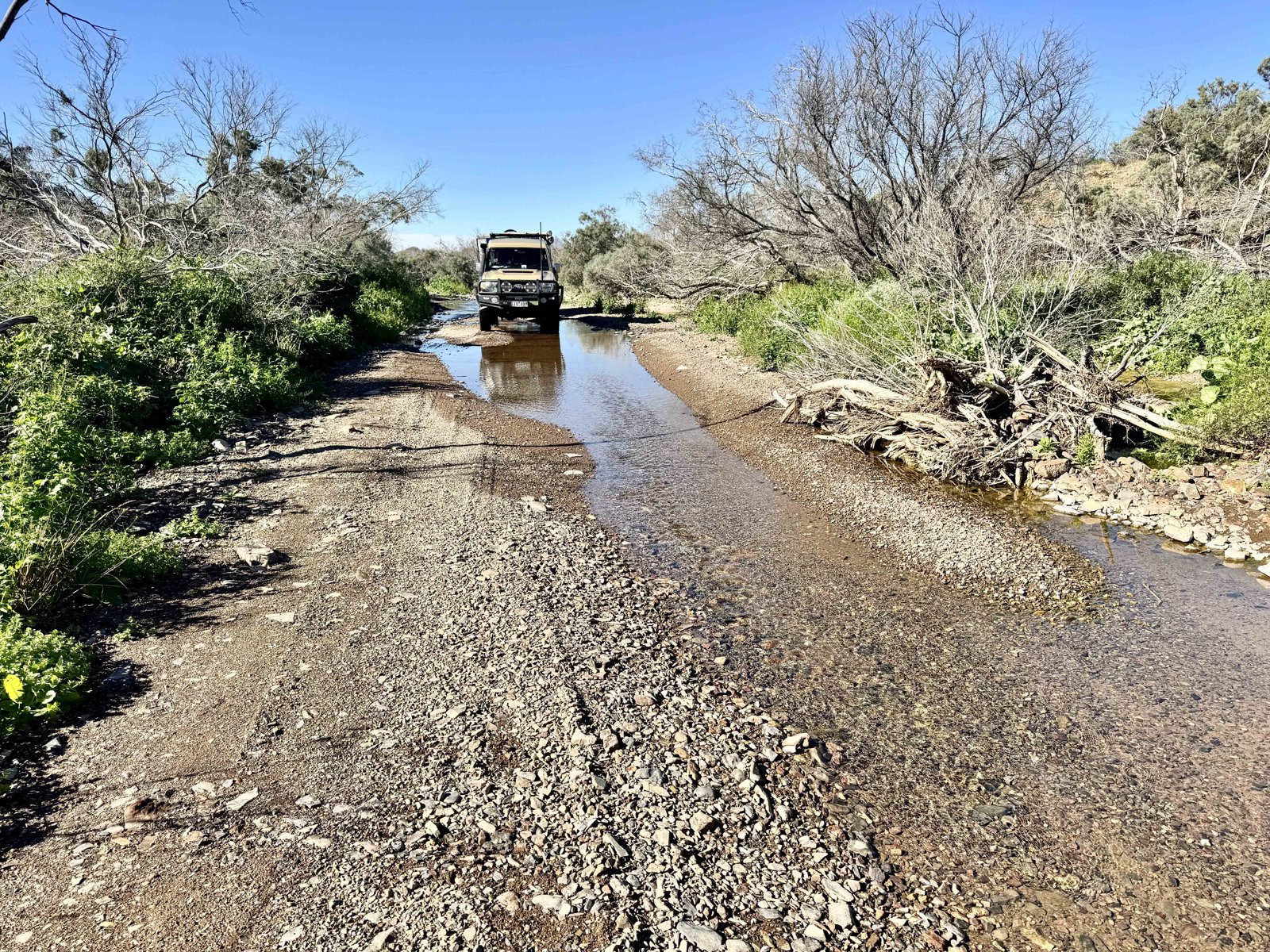 溪水仍流过路面，洪水留下的漂浮物堆在岸边。