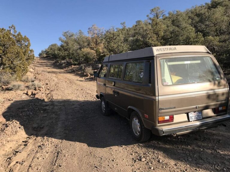 棕色大众露营车停在阳光下的碎石山路上