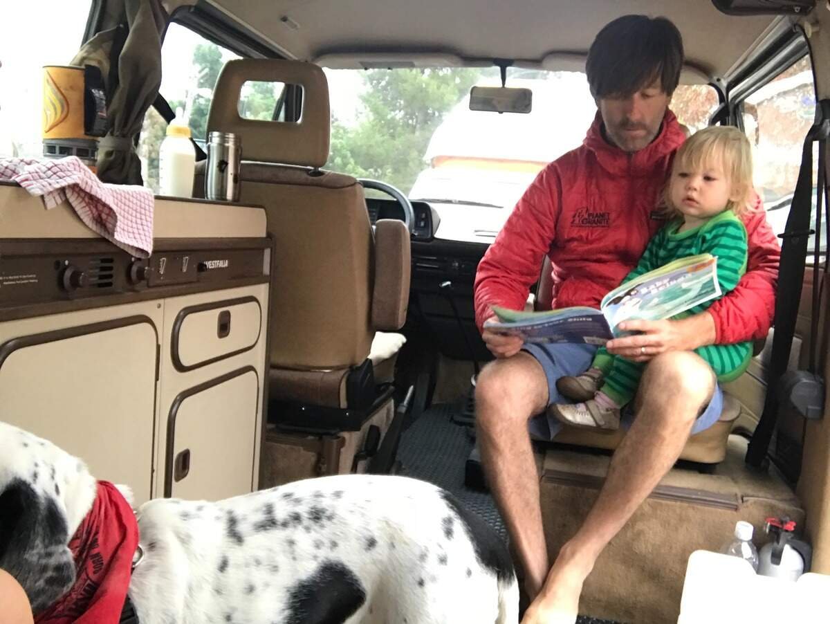 男子在房车内给穿绿衣的孩子读绘本