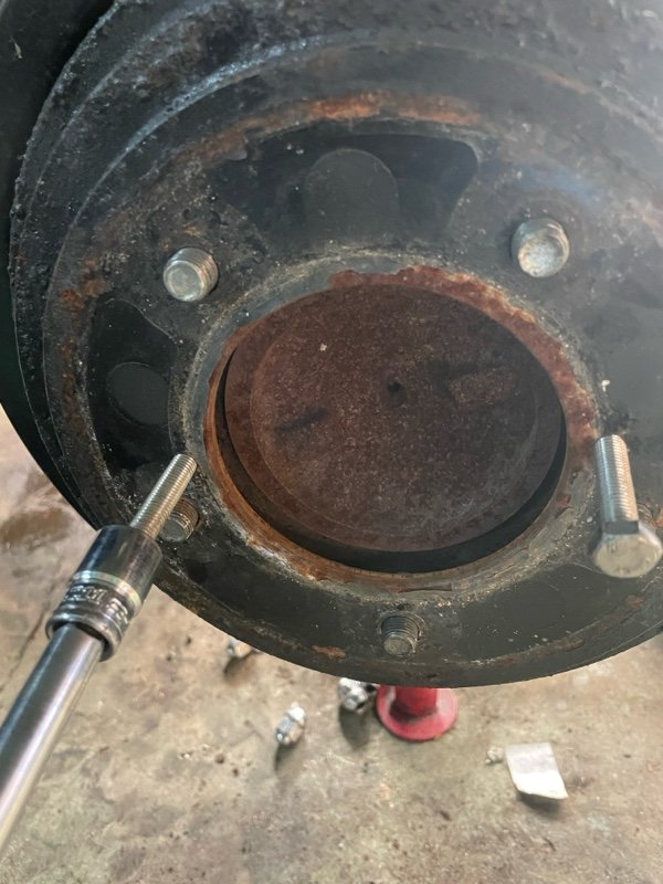 生锈车轮毂上连接着银色液压拉马工具
