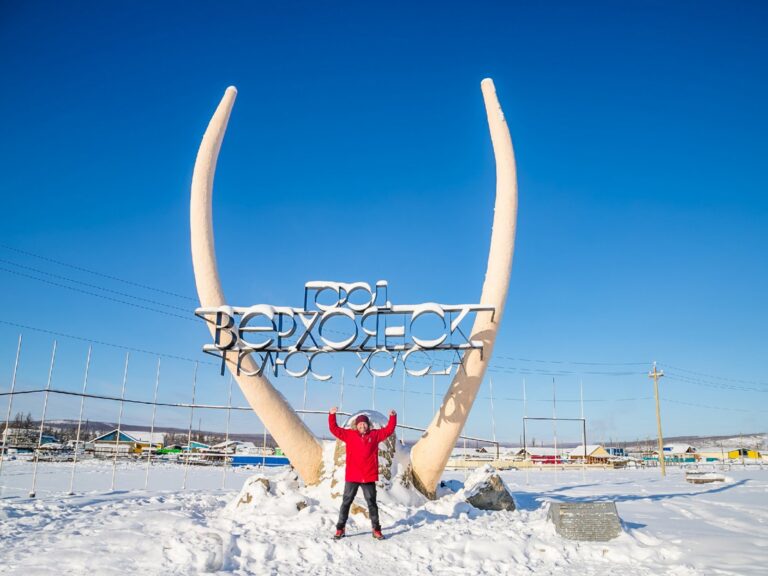 男子在雪地中张开双臂站在猛犸象牙地标前