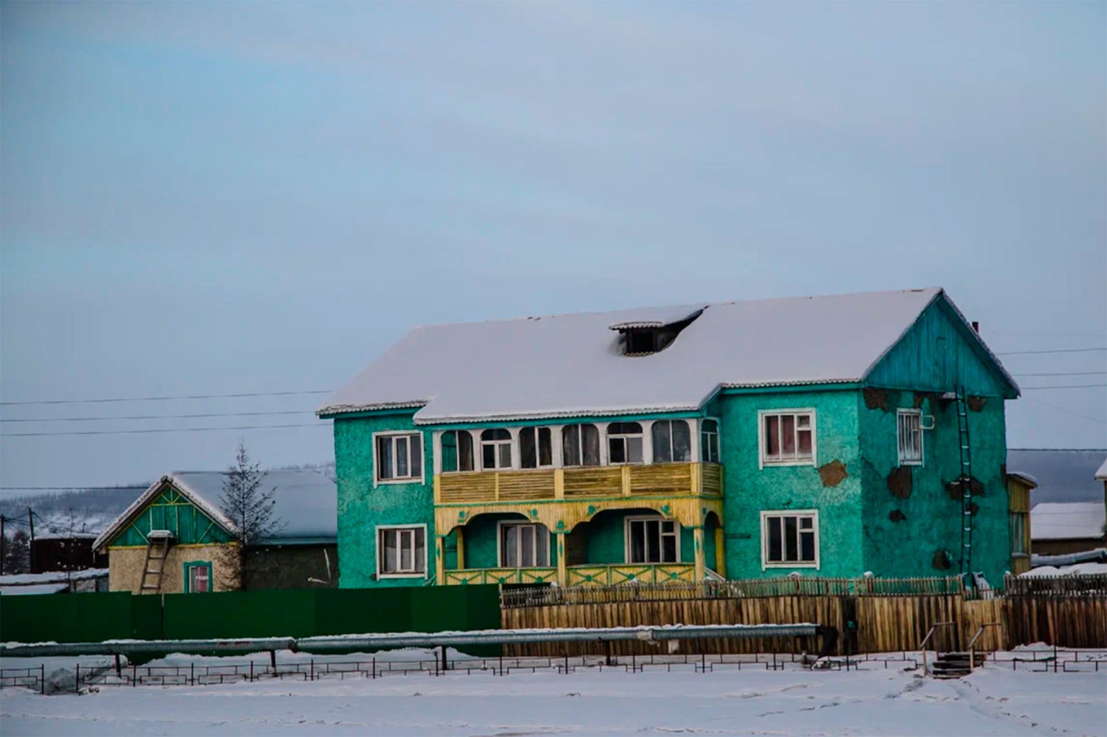 雪地中一栋外墙斑驳的绿色多层建筑